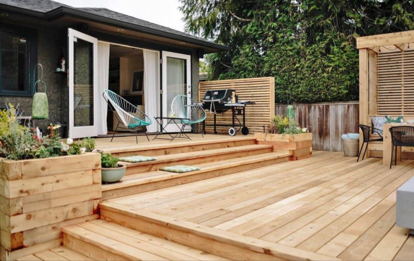 Backyard deck arranged with planters and a barbecue