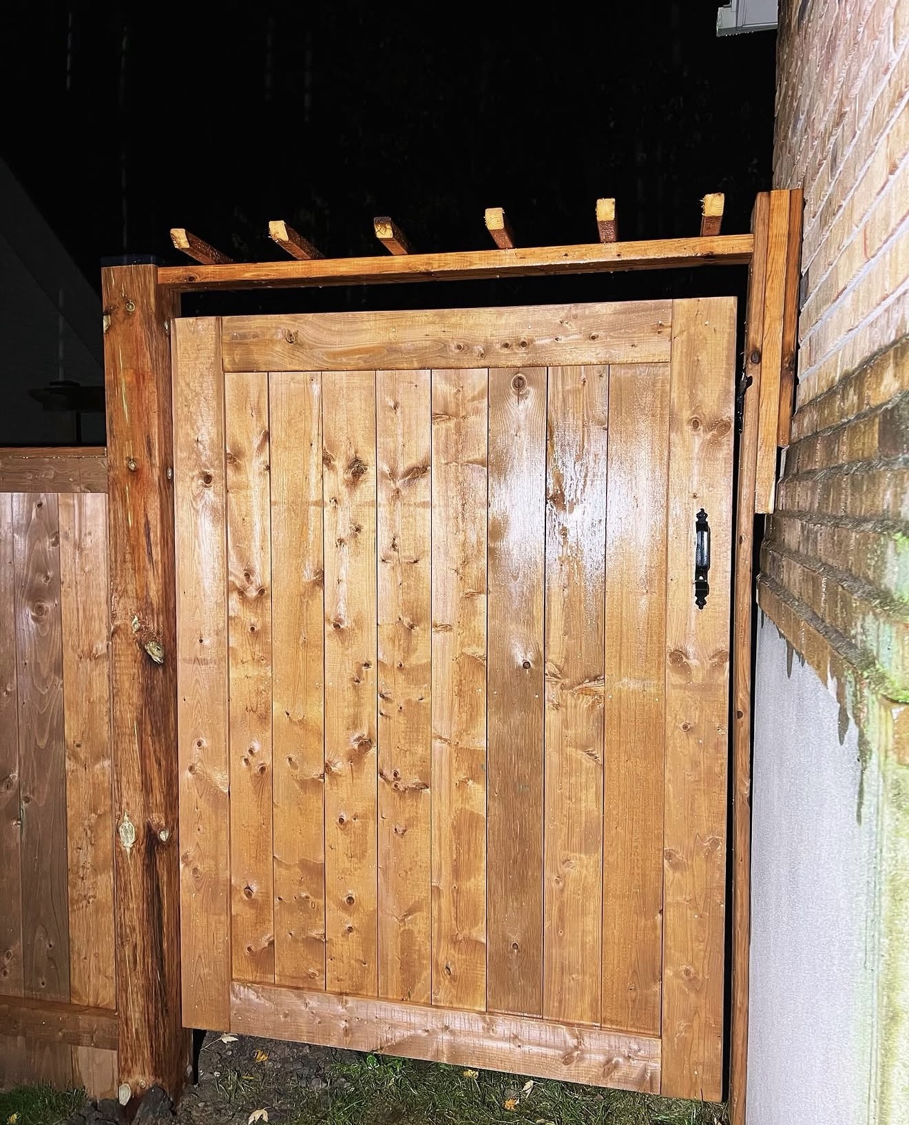 Custom full-height wooden side gate photographed at night