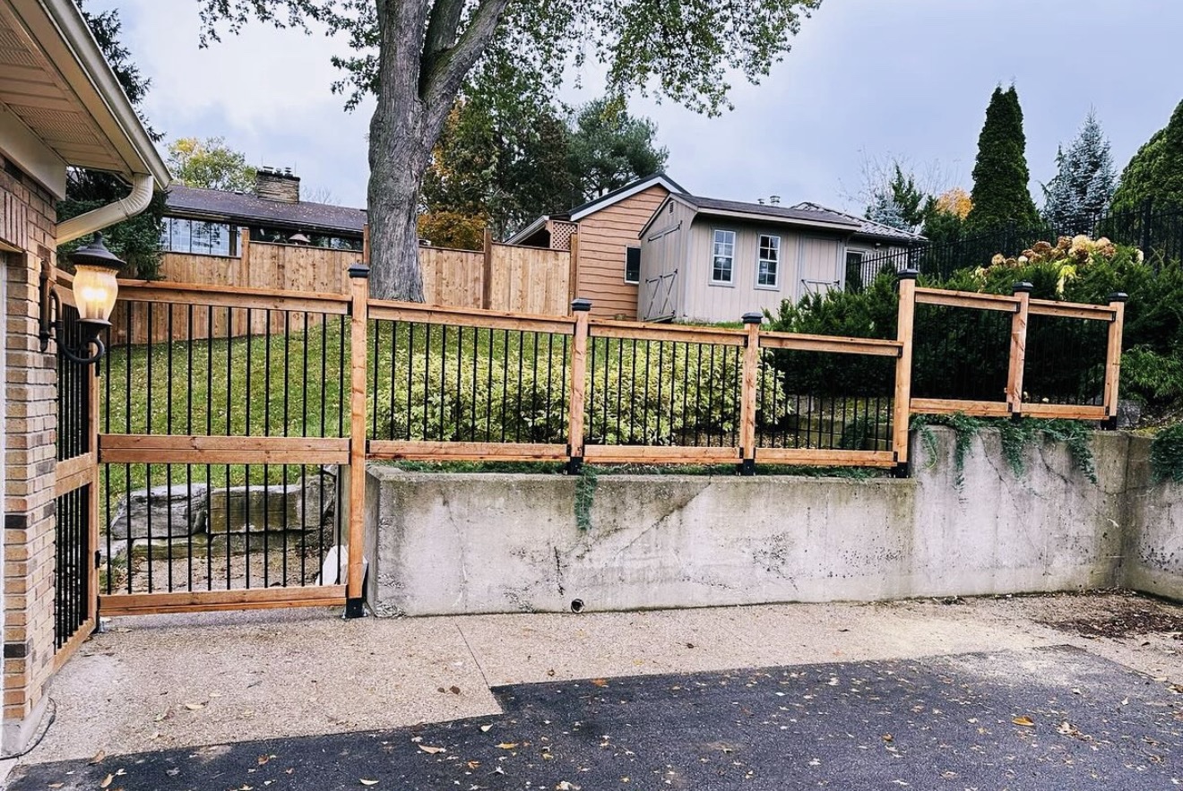 Custom wood-and-black-metal railing installed over a concrete retaining wall